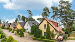 A row of modern houses with a paved driveway, neatly trimmed hedges, and a clear sky. - Apartment 'Haus 19 OG' with Private Garden, Balcony and Wi-Fi (Röbel)