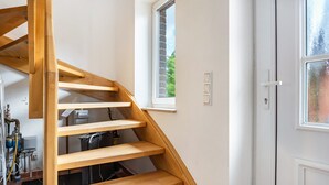 A wooden staircase with a window above it, a white door, and visible plumbing in the background. - Apartment 'Haus 19 OG' with Private Garden, Balcony and Wi-Fi (Röbel)