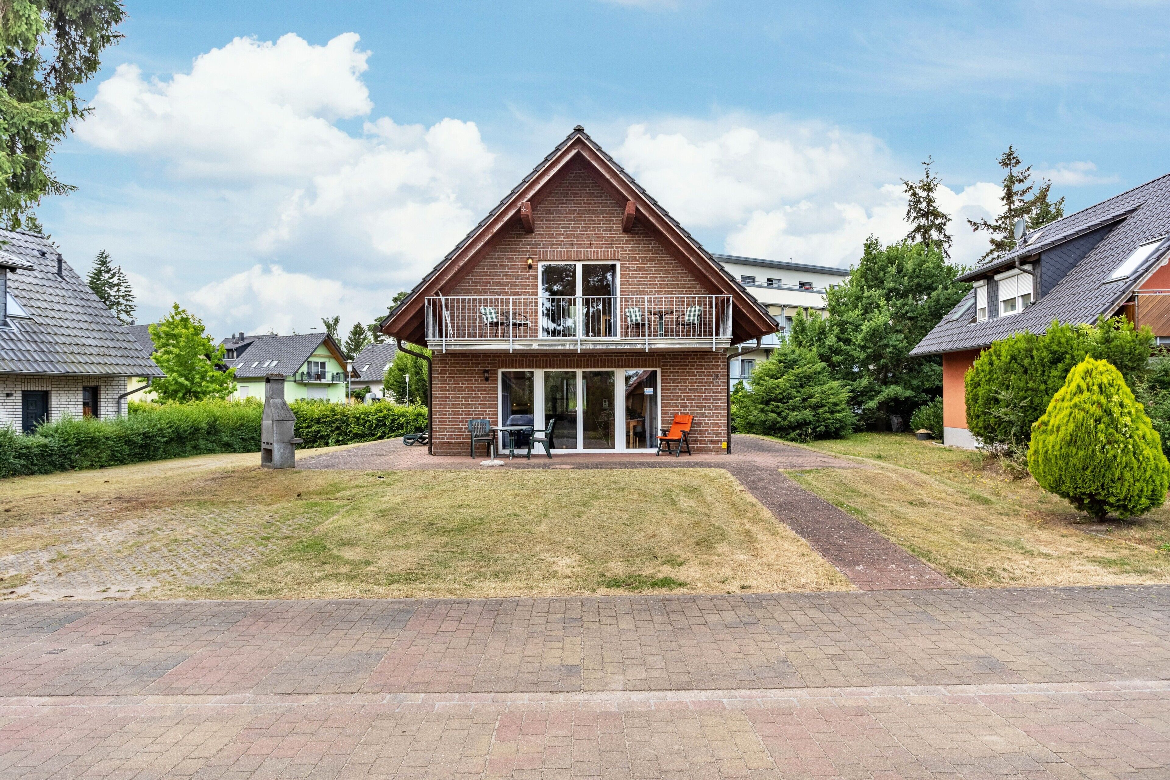 Une maison à deux étages avec un balcon, une allée pavée et une pelouse bien entretenue.