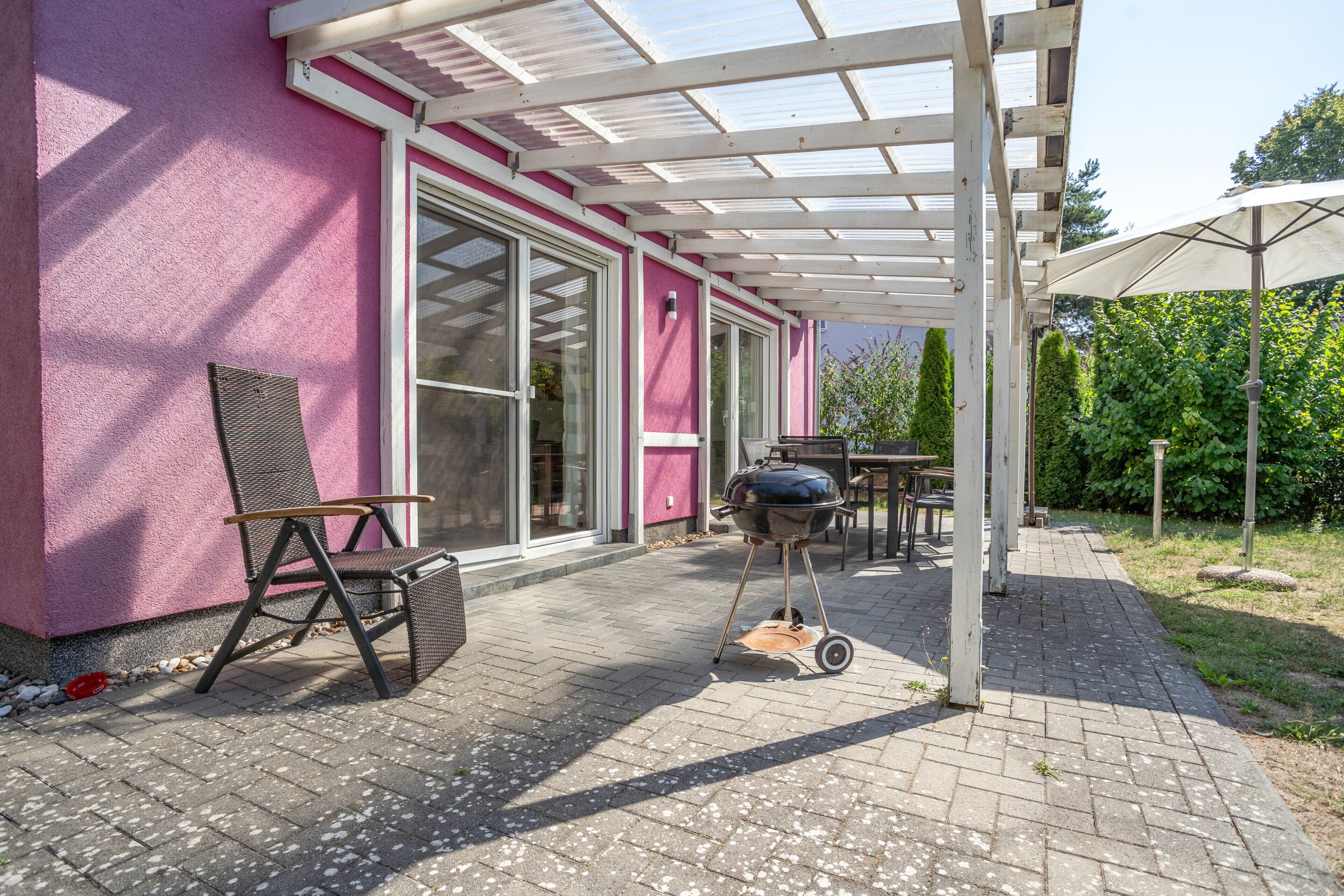 A covered patio area with a grill, outdoor furniture, and a pergola.