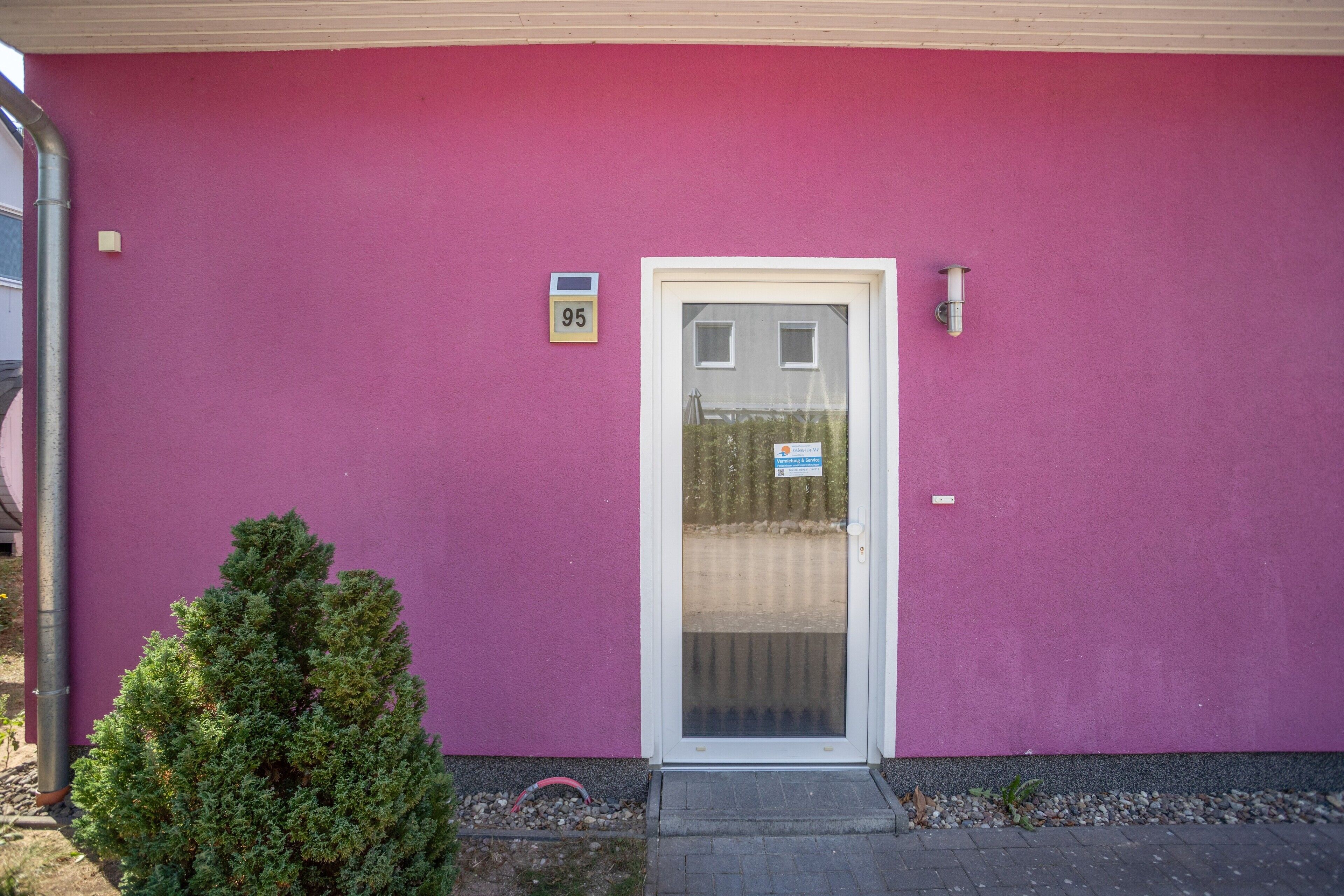 Un bâtiment à la façade rose, avec une porte blanche et une petite enseigne portant le numéro 95.