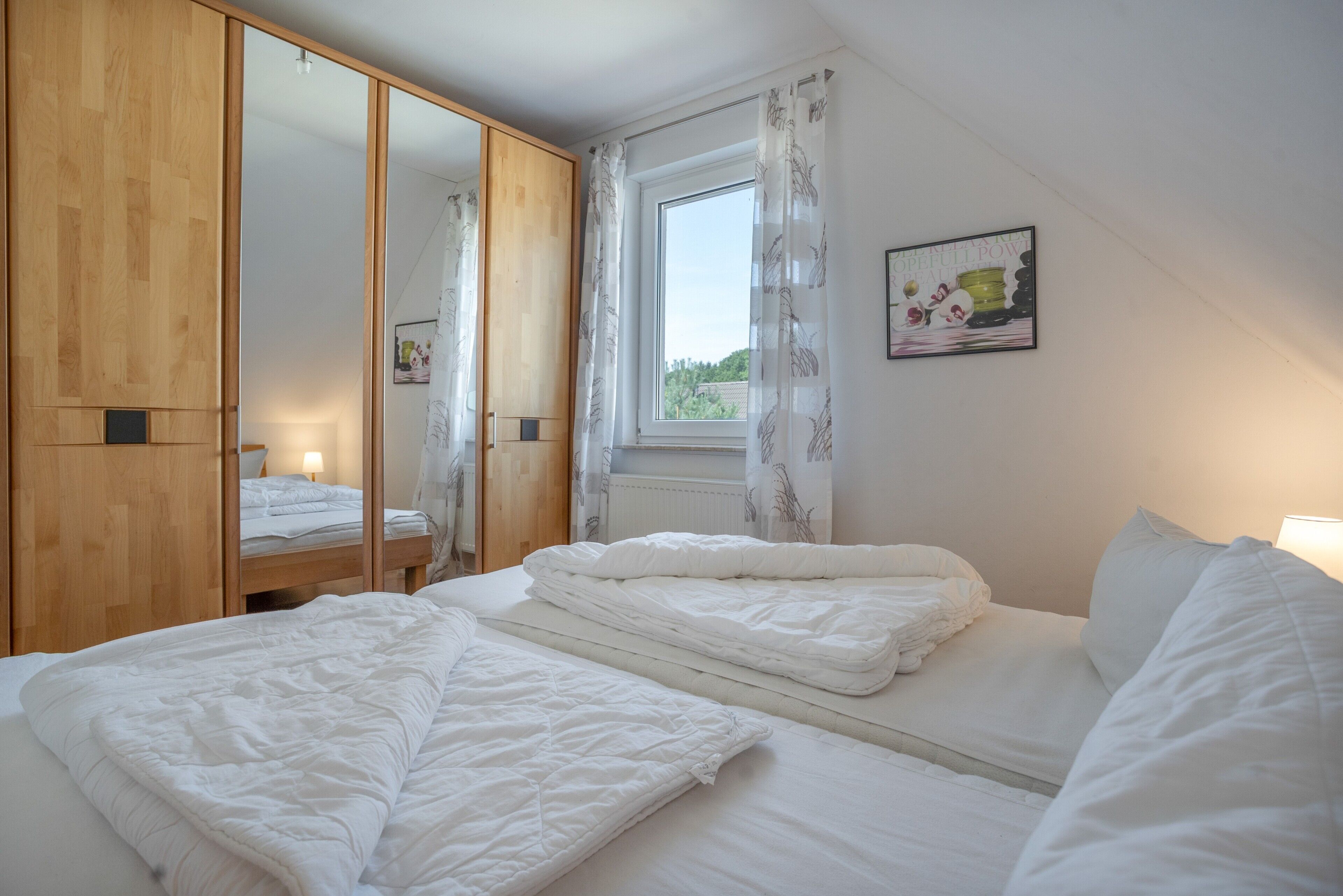 Une chambre à coucher avec un lit, une armoire, une fenêtre avec des rideaux et un tableau accroché au mur.