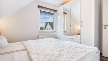 Ein Schlafzimmer mit Bett, Kleiderschrank, Fenster und Heizkörper.