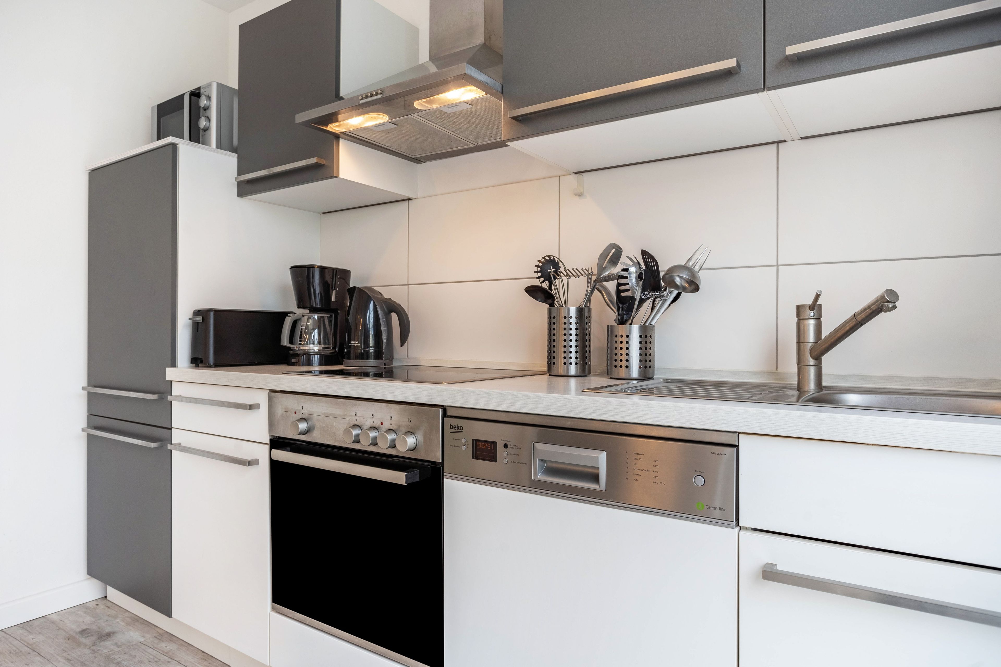 A modern kitchen with a built-in oven, dishwasher, and coffee maker.