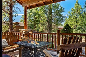 Eine Terrasse mit Feuerstelle, Holzstühlen und einer Steinmauer.