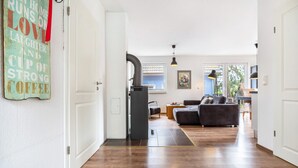 Moderni olohuone, jossa on sohva, ruokailutila ja avoimen oven kautta näkyvä keittiö.
