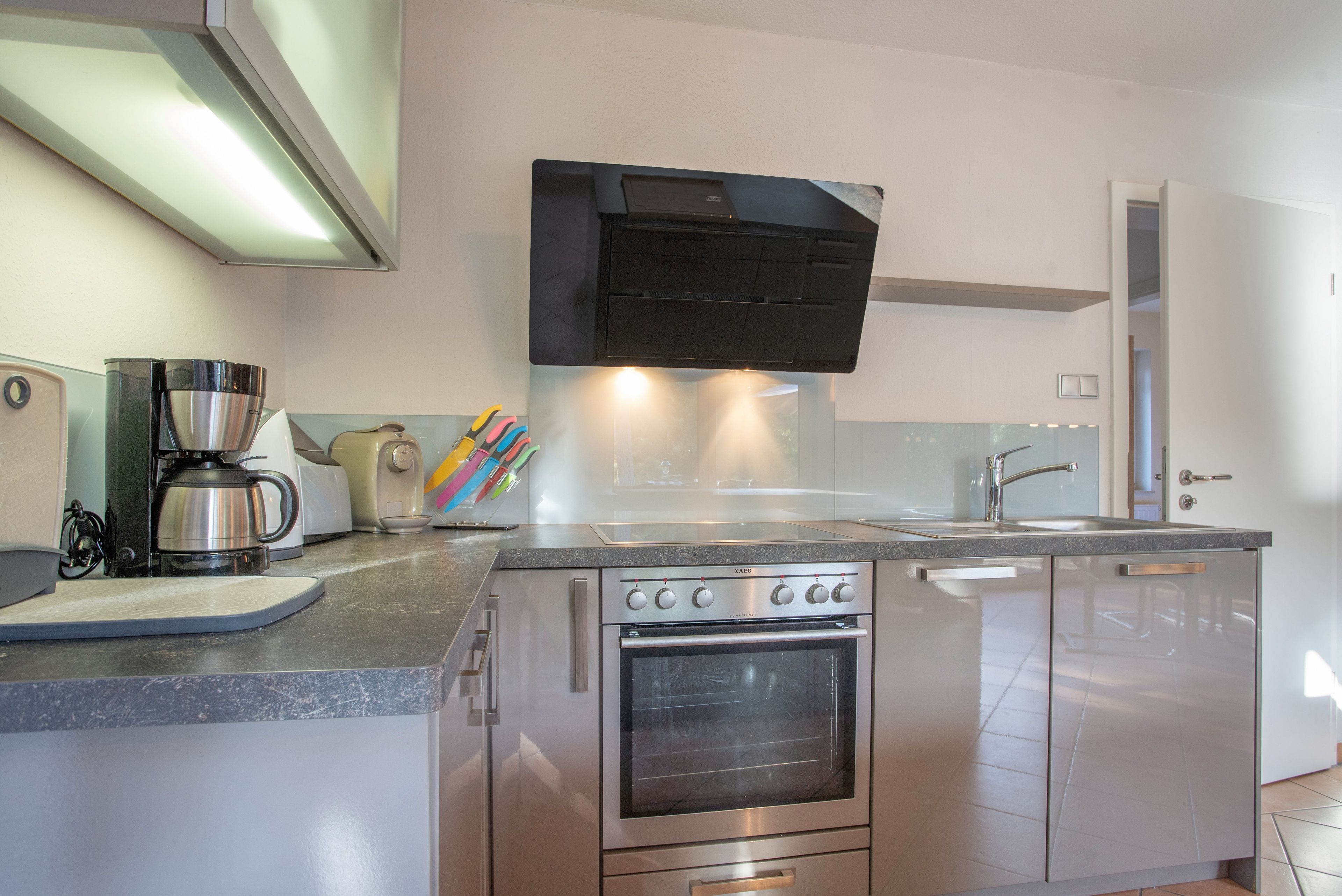 A compact kitchen with a built-in oven, a coffee maker, and a toaster.