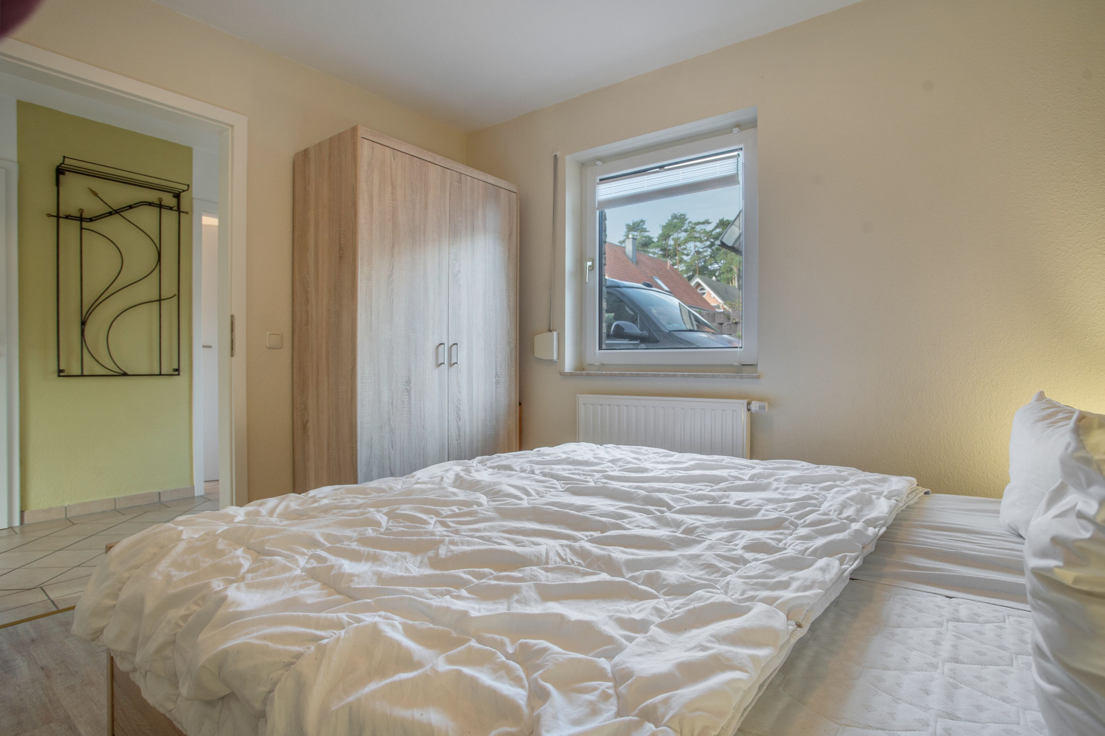 A bedroom with a bed, a wardrobe, a window, and a radiator.