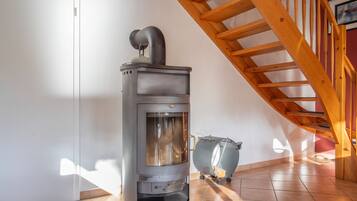A modern kitchen with a built-in wood stove, a wooden staircase, and a tiled floor.