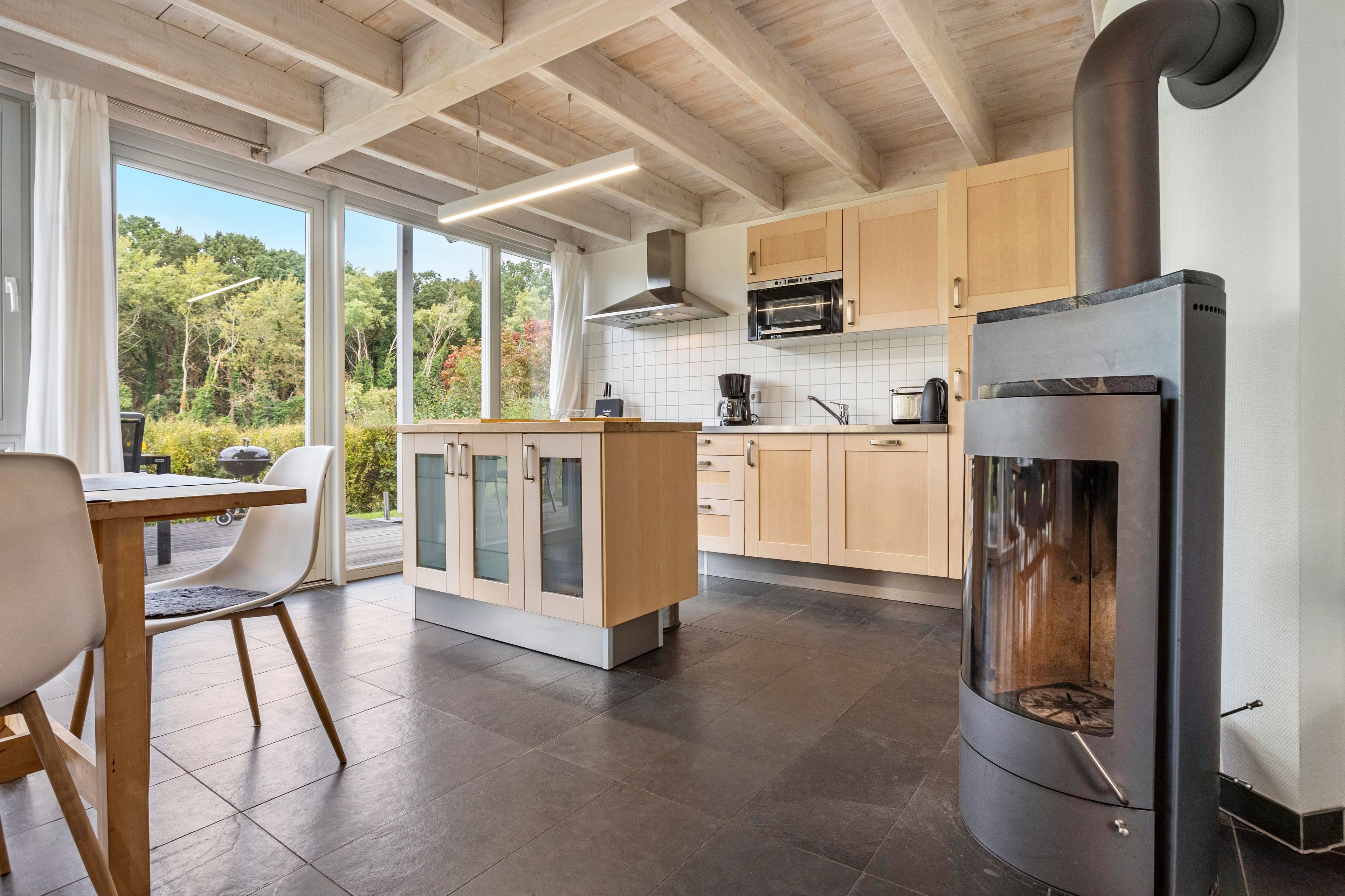Une cuisine moderne dotée d’une cuisinière intégrée, de meubles en bois et d’un coin repas avec une table et des chaises.
