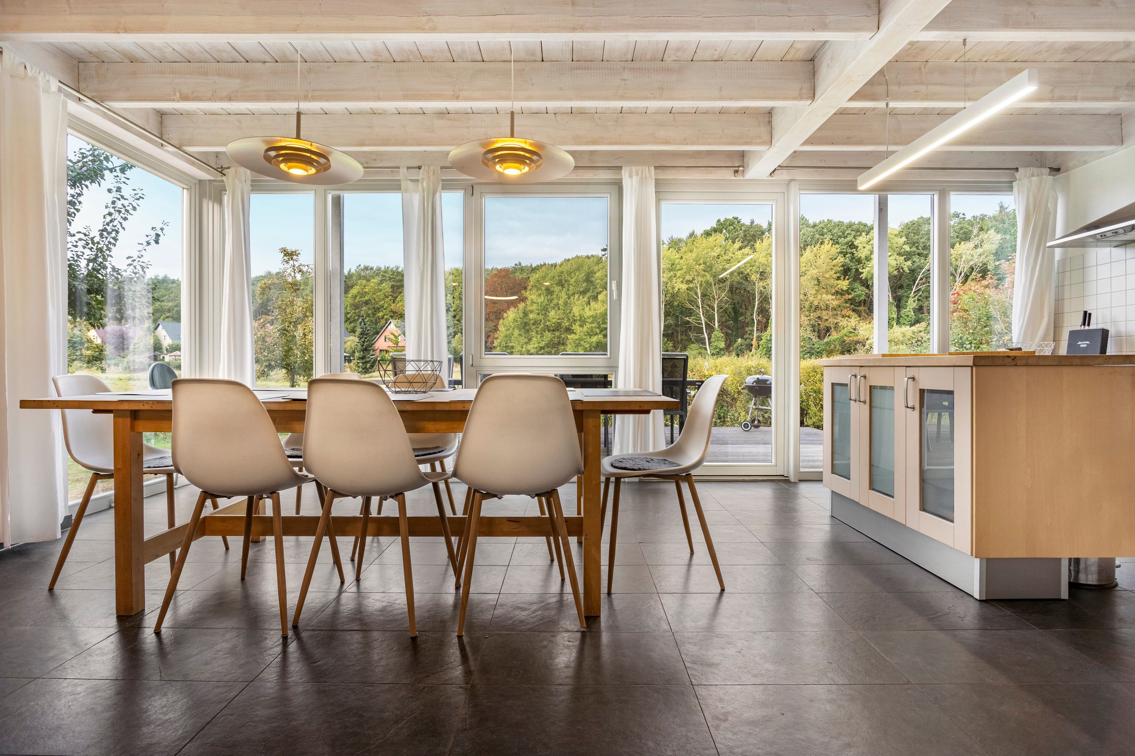 A modern kitchen with a large dining table, four chairs, and a kitchen island with cabinets.