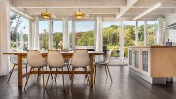 A modern kitchen with a large dining table, four chairs, and a kitchen island with cabinets.