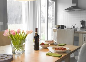 Eine moderne Küche mit Esstisch, gedeckt für eine Mahlzeit, einer Tulpenvase und einer Weinflasche.