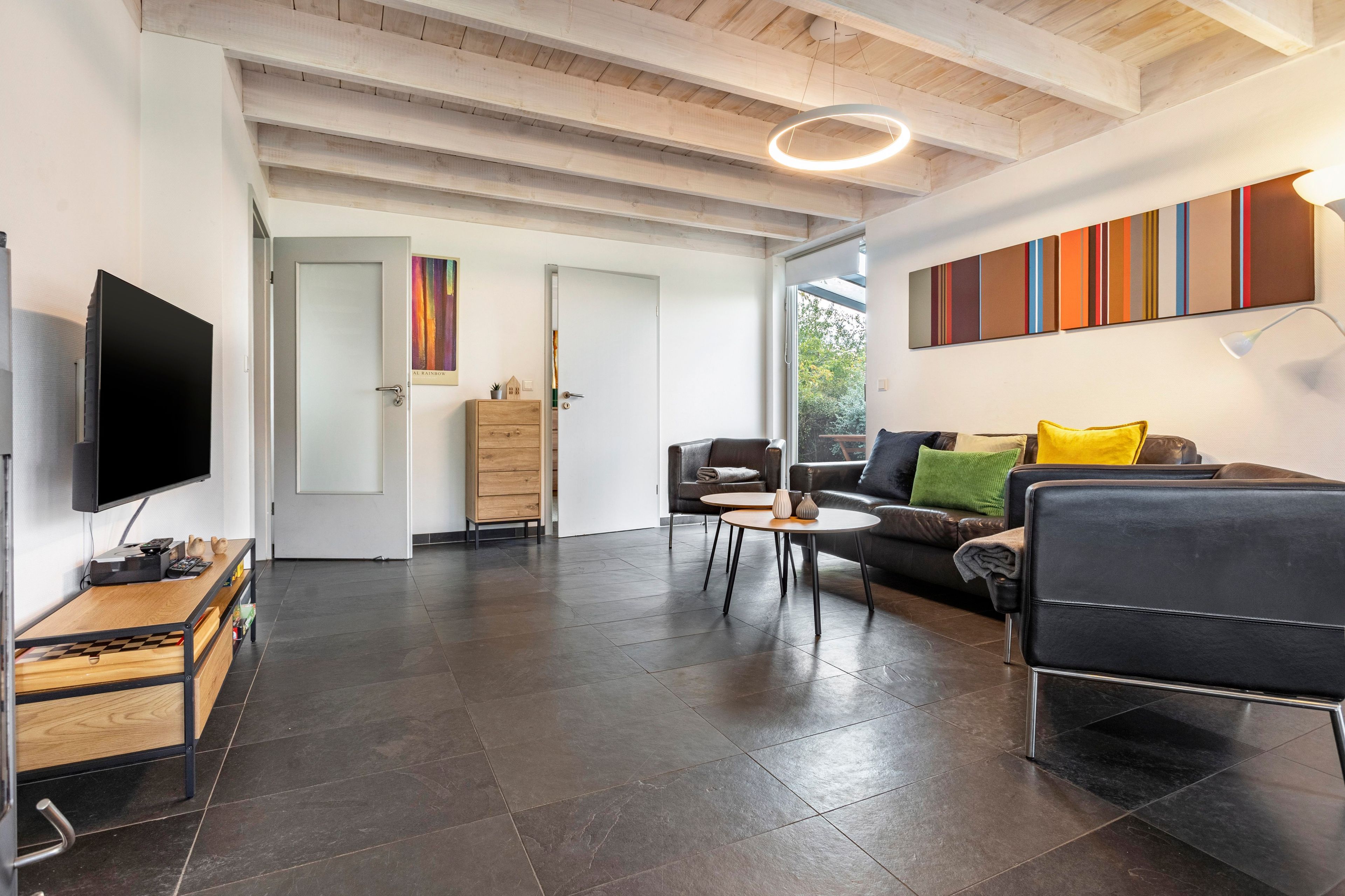 A modern living room with a flat-screen TV, a sofa, a coffee table, and a fireplace.