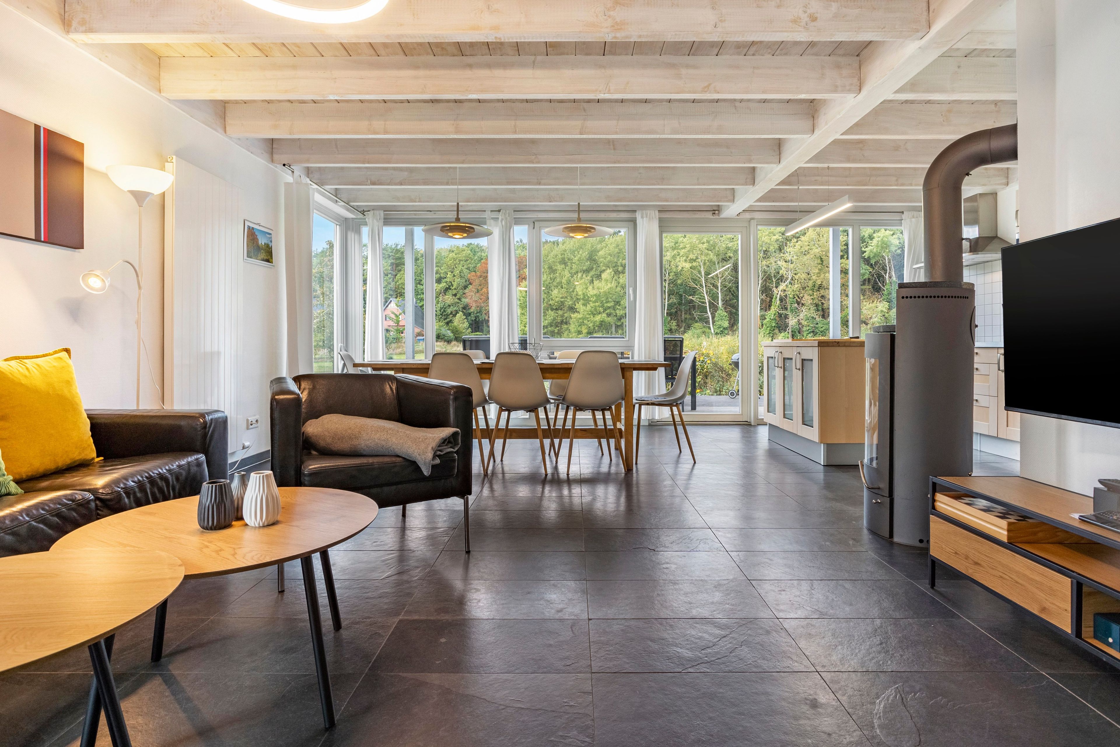 A modern interior with a dining area, sofas, and a large TV.