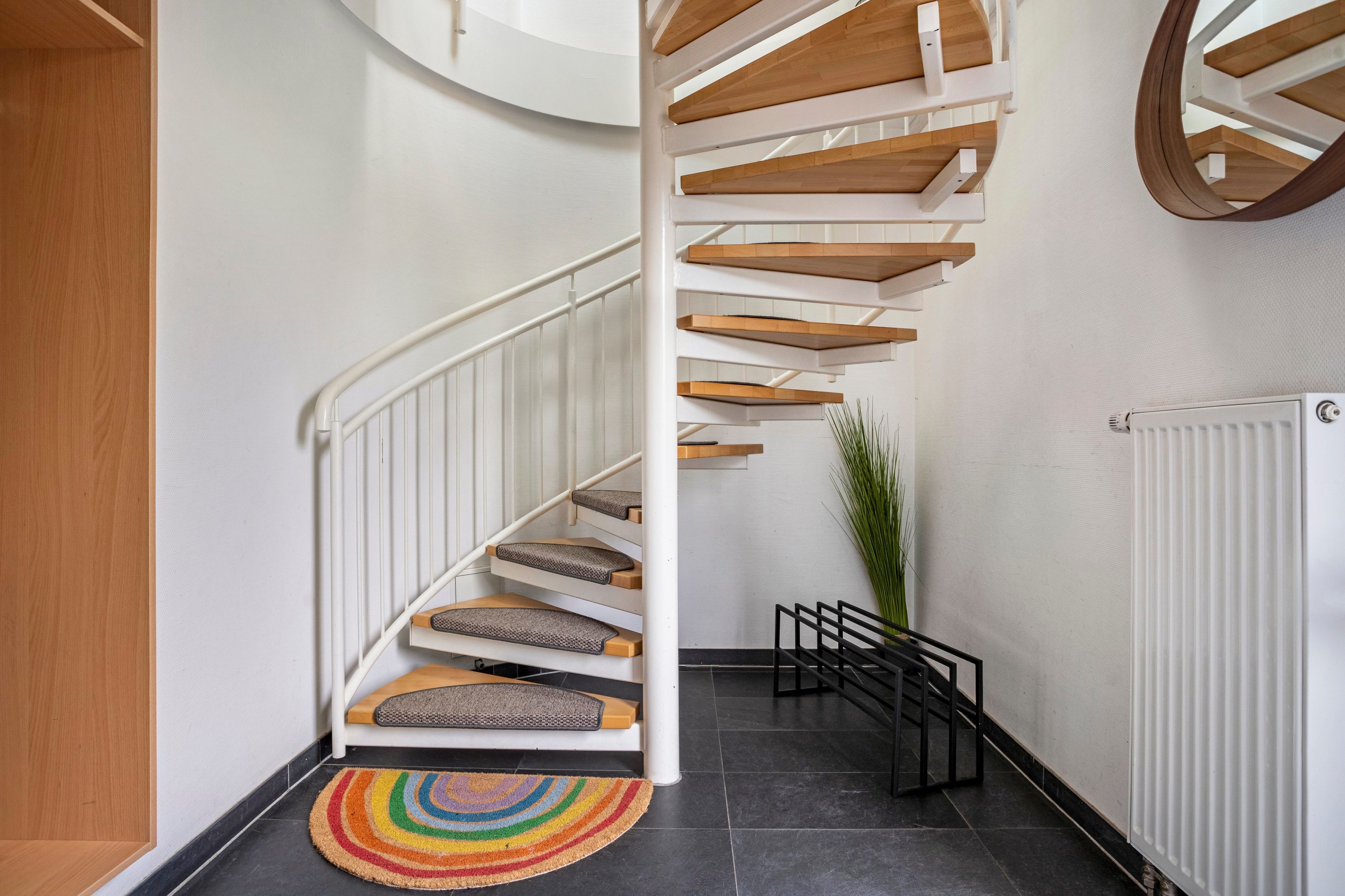 A spiral staircase with wooden steps and white railings, leading to an upper floor.