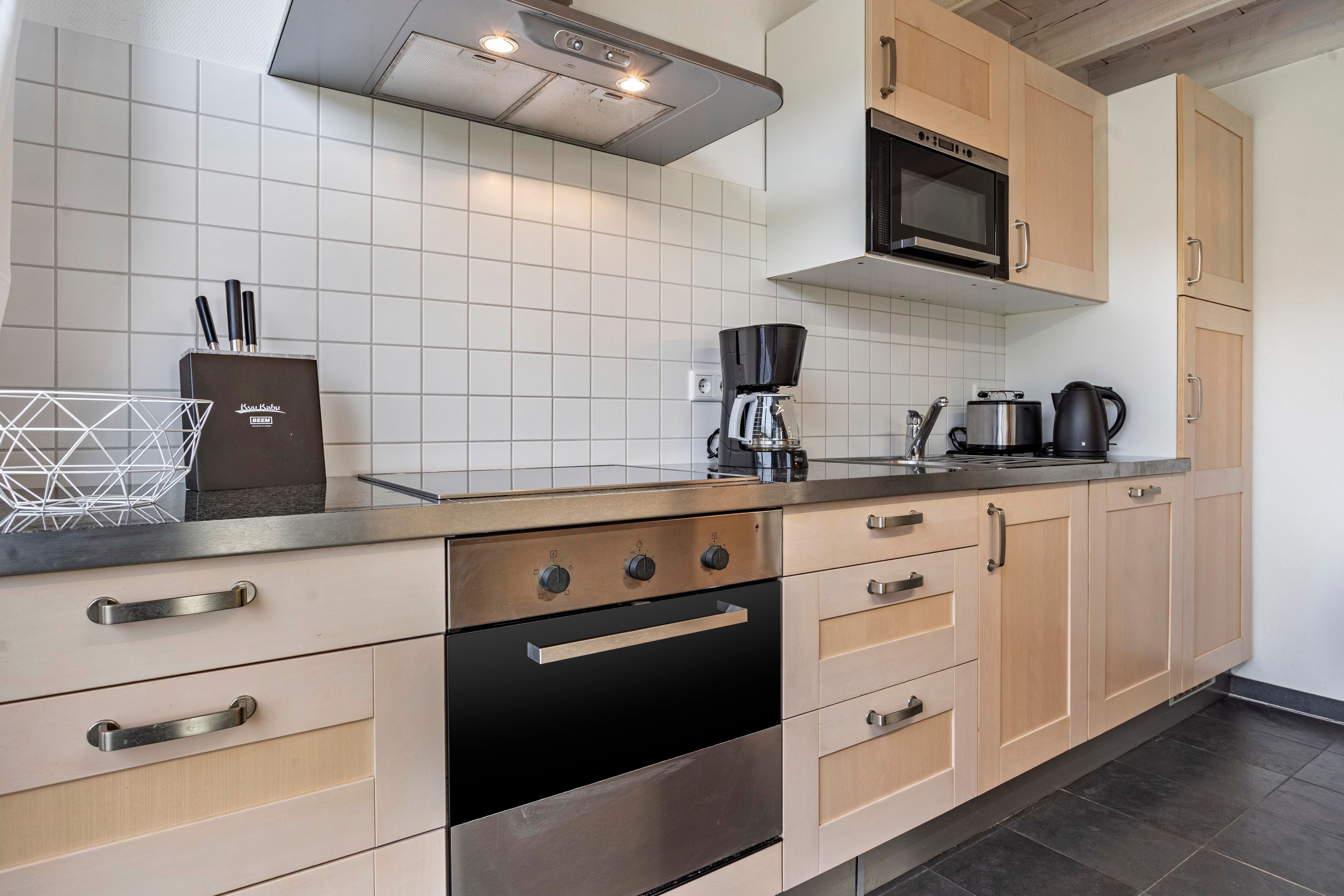 Una cocina moderna con estufa de acero inoxidable, microondas integrado y cafetera.