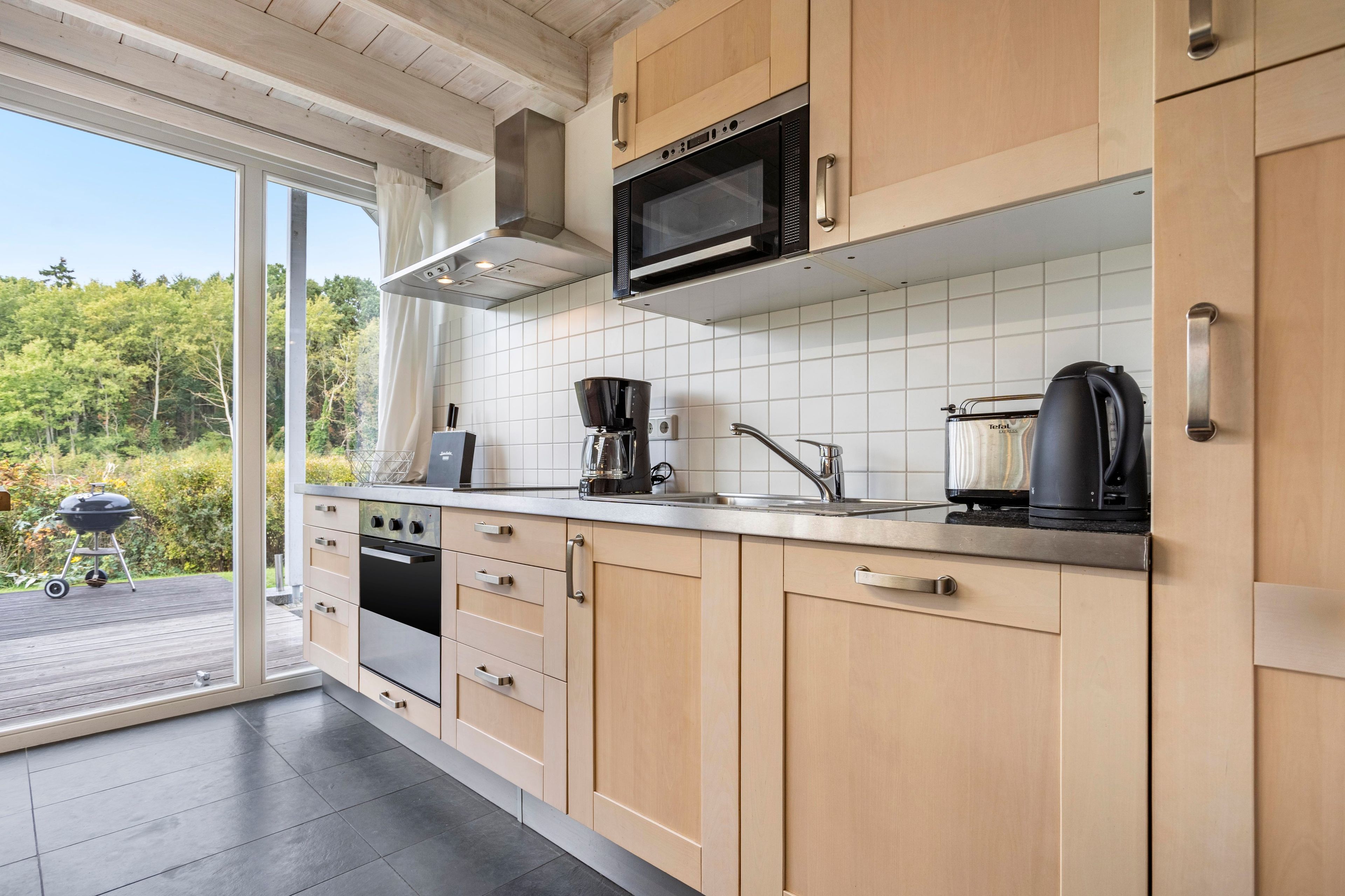 A modern kitchen with wooden cabinets, a stainless steel sink, and a built-in microwave.