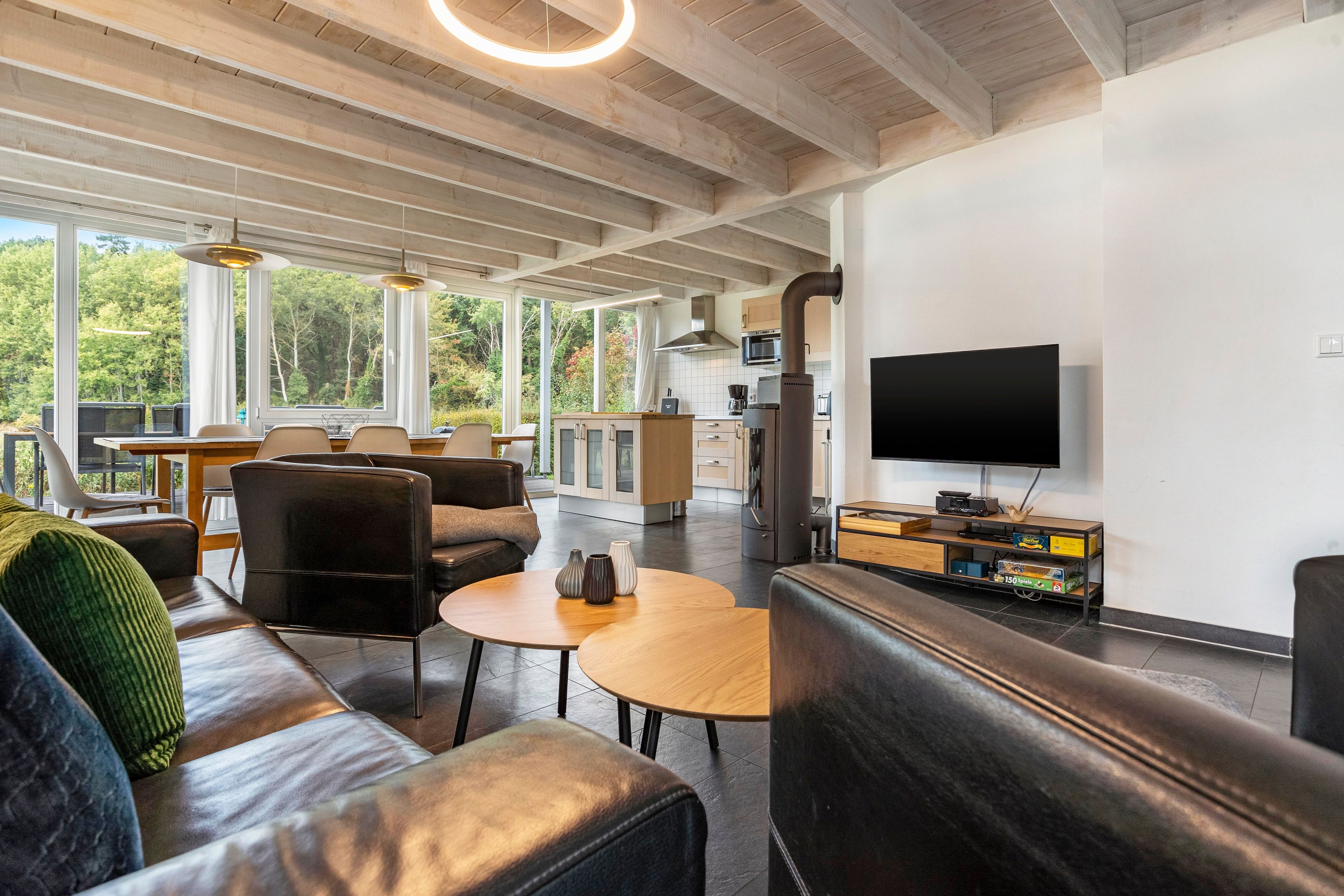 Ein modernes Wohnzimmer mit einer Couch, zwei Sesseln, einem Couchtisch und einem Fernseher.