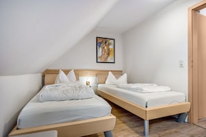 Ein Schlafzimmer mit zwei Einzelbetten, einem Nachttisch mit Lampe und einem gerahmten Kunstwerk an der Wand.