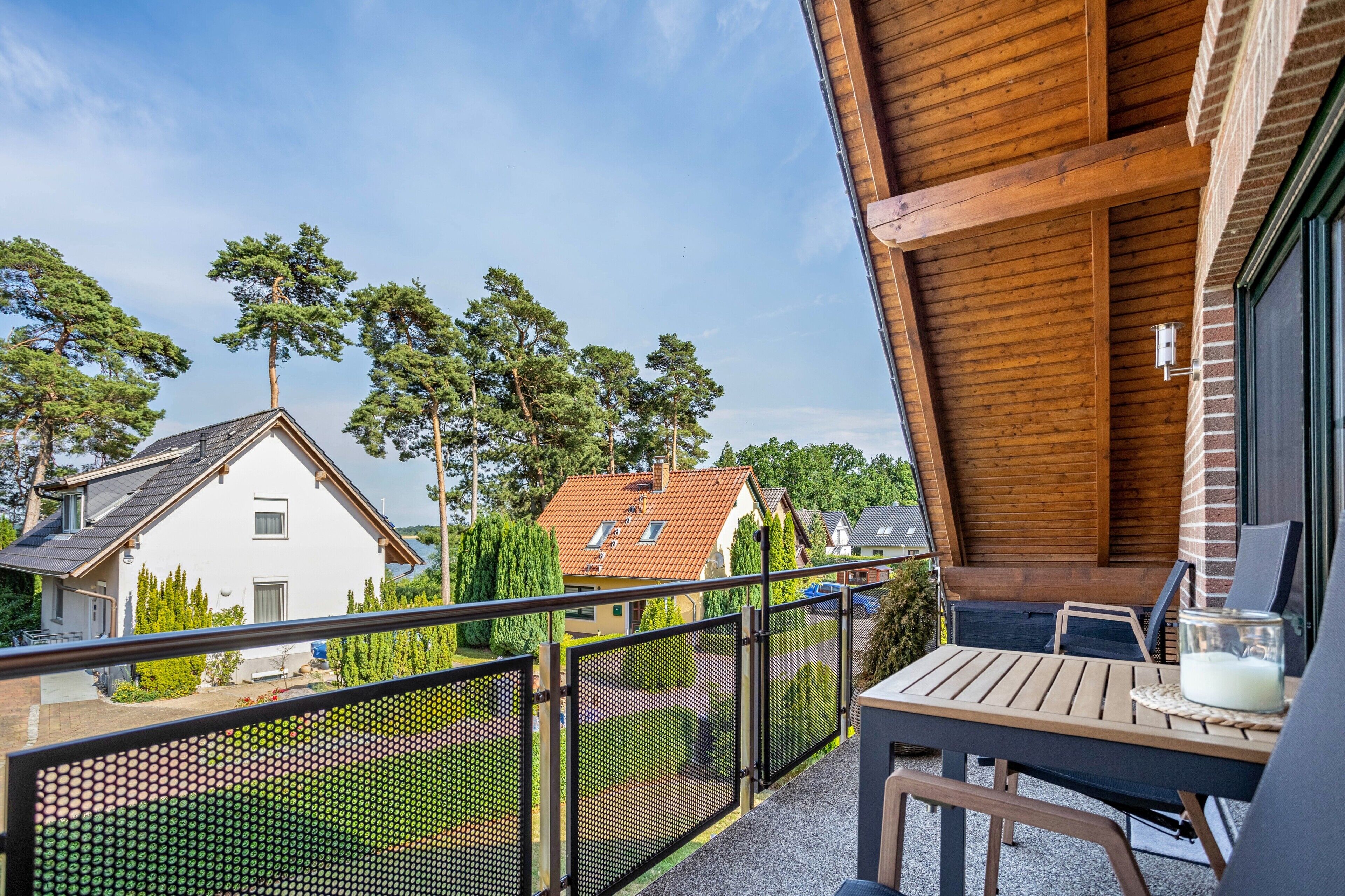 Ein Balkon mit Tisch und Stühlen, Blick auf Häuser und bewölkter Himmel.
