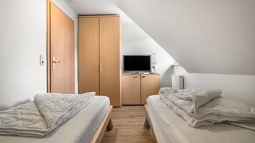 Ein Schlafzimmer mit zwei Betten, einem Kleiderschrank, einem Fernseher und einer Heizung.