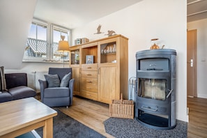 Ein gemütliches Wohnzimmer mit einer Couch, einem Holzschrank mit Gläsern, einem Kamin und einem Fenster mit Blick.