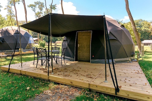 Ein Campingplatz mit einem großen Zelt, einem Esstisch und Stühlen.