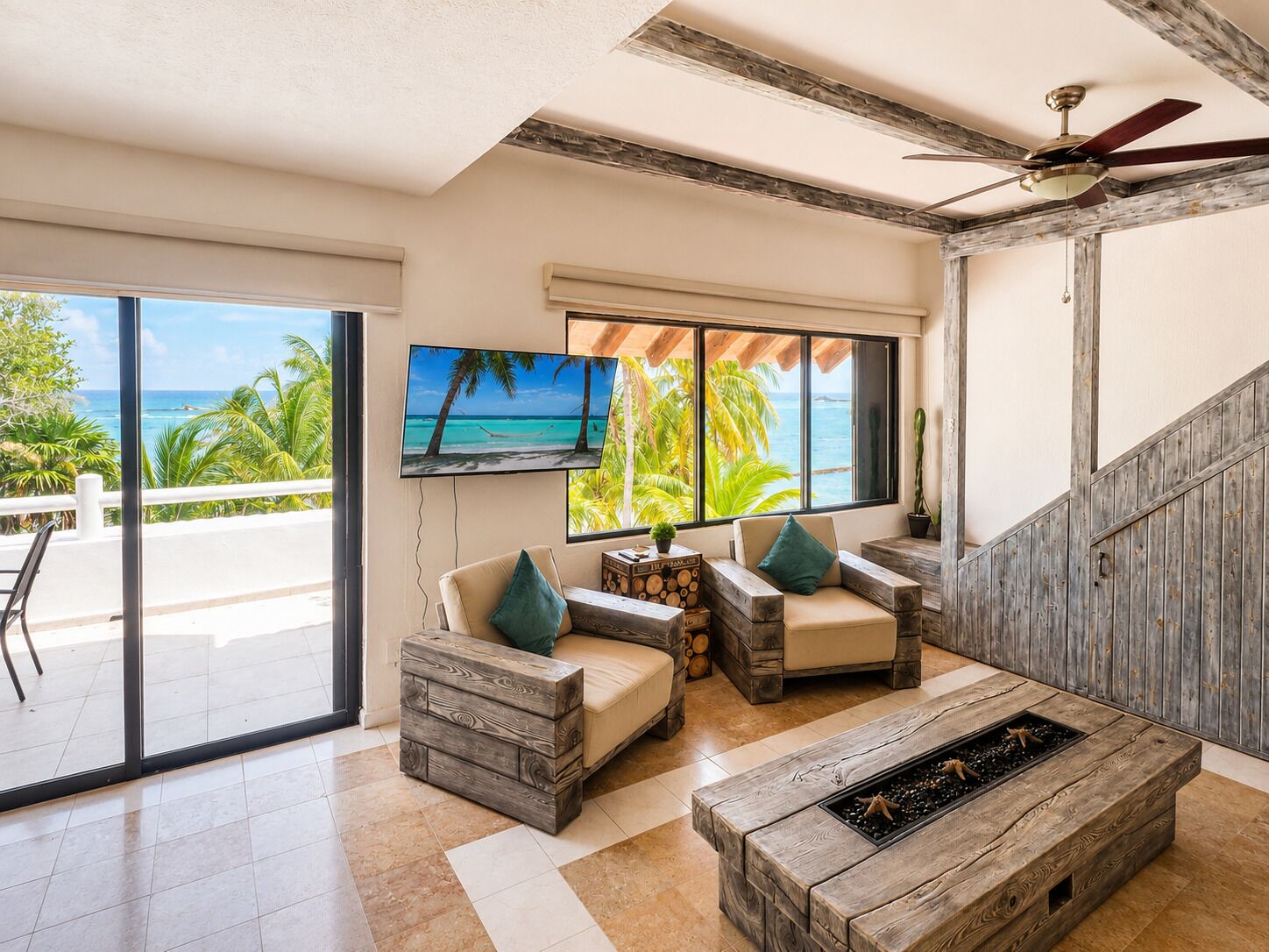 Amplia sala de estar con un televisor grande, muebles de madera y vista al océano.