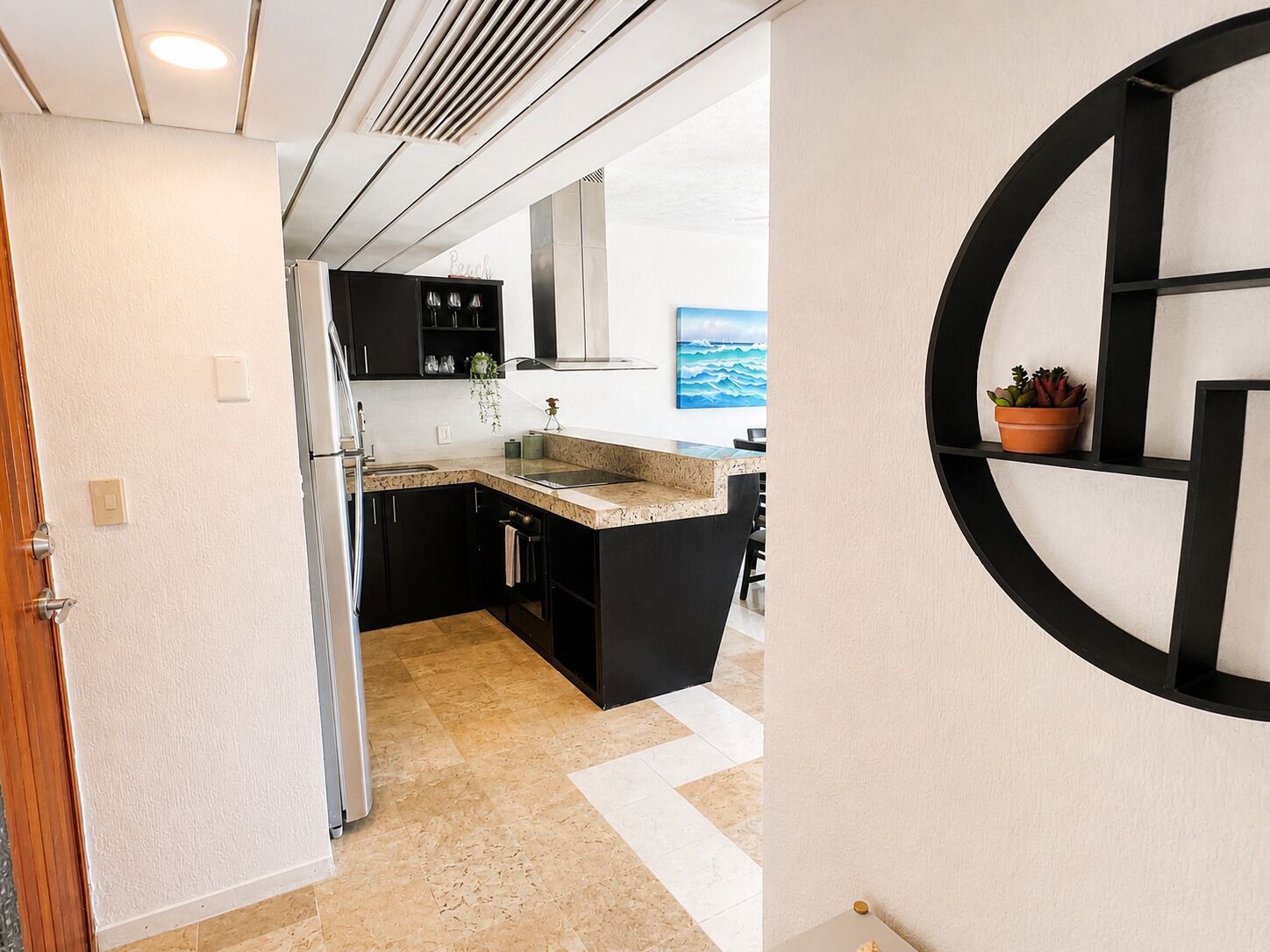 A modern kitchen with black cabinets, a granite countertop, and a potted plant.
