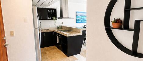 A modern kitchen with black cabinets, a granite countertop, and a potted plant.