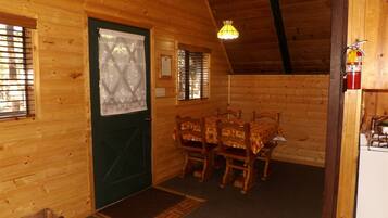 Un intérieur en bois avec une table et des chaises, une porte verte et un extincteur.