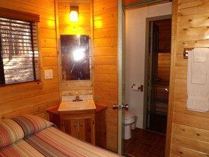 A wooden cabin interior with a bed, a sink, and a toilet. - Marvelous Lofted Cabin Incredible for Nature Lovers in Arizona (Flagstaff)