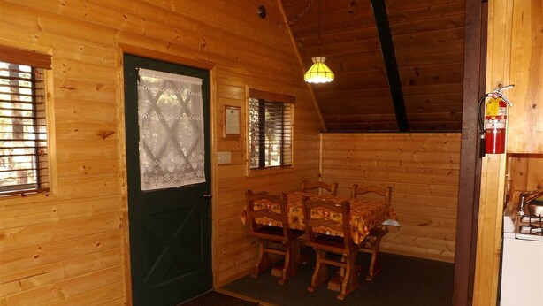 Un interior de madera con una mesa de comedor, sillas, una puerta verde y un extintor.