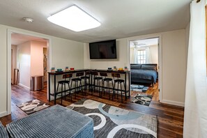 Een kleine woonruimte met een keukenhoek, een eettafel met stoelen, een bank en een bed.