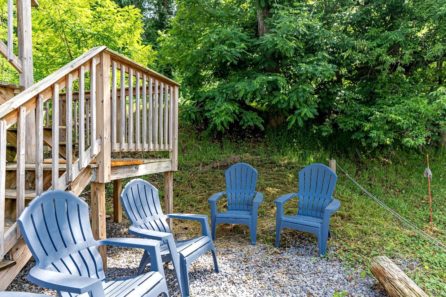 A wooden deck with a railing, surrounded by greenery.
