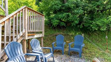 A wooden deck with a railing, surrounded by greenery.