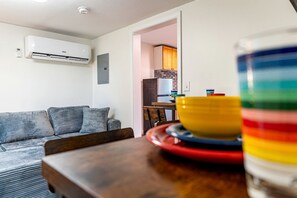 Ett vardagsrum med en soffa, ett matbord med en skål på och en luftkonditioneringsanläggning på väggen.