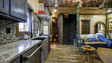 A rustic interior with a stone kitchen, wooden floors, and a cozy seating area.