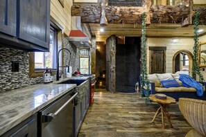 Un interior rústico con cocina de piedra, suelos de madera y una zona de estar acogedora.