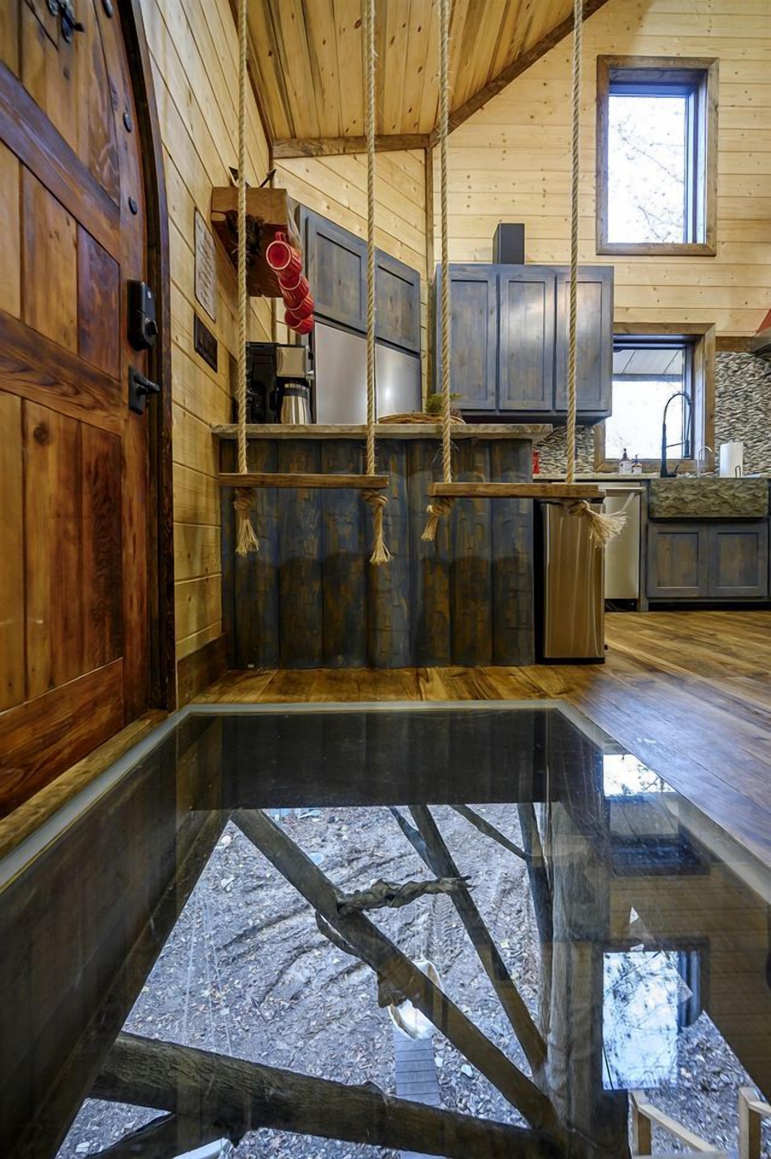 A wooden interior with a glass floor, wooden cabinets, and a window.