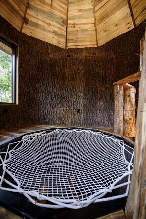 A room with a circular netted floor, wooden walls, and a window. - Gorgeous Tree House with Hot-tub in Broken Bow, Oklahoma (Broken Bow)