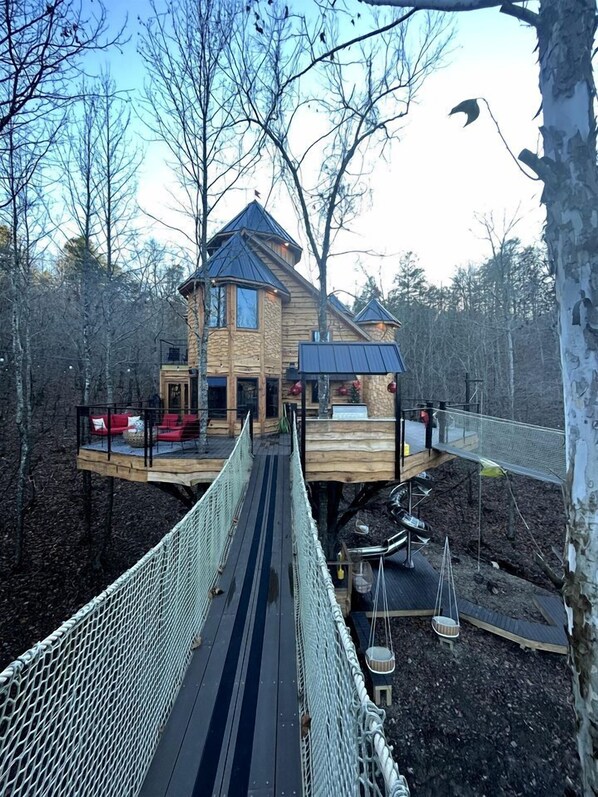 A wooden house with a deck and a rope bridge. - Gorgeous Tree House with Hot-tub in Broken Bow, Oklahoma (Broken Bow)
