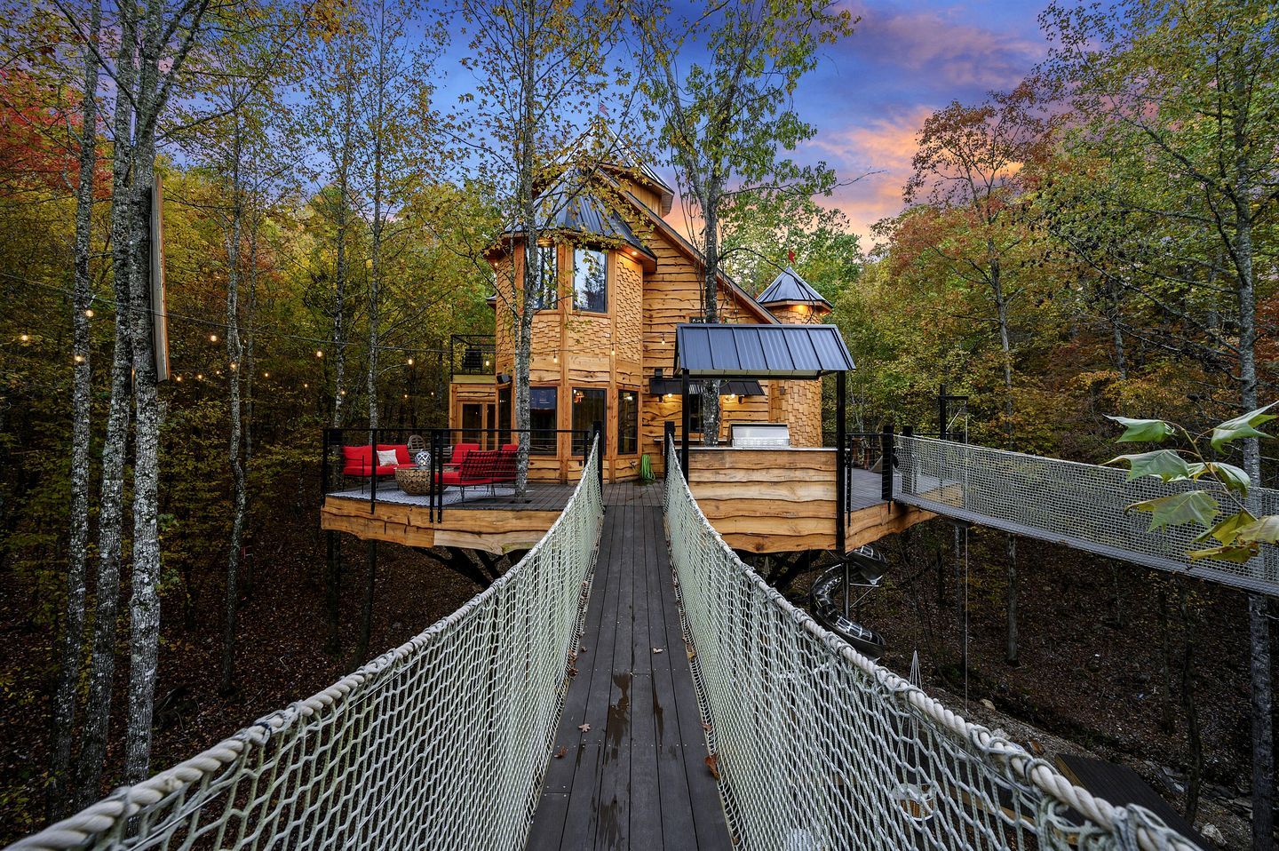 A wooden cabin with a deck, surrounded by trees.