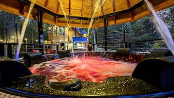 Un jacuzzi con chorros de agua, rodeado de muebles de madera y una vista de un edificio al fondo.