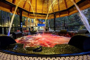 A hot tub with water jets, surrounded by wooden furniture and a view of a building in the background.