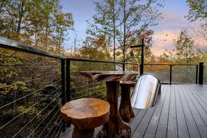A wooden deck with a metal railing, a bench, and a table.