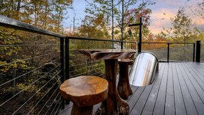 Een houten terras met een metalen hekwerk, een bank en een tafel.