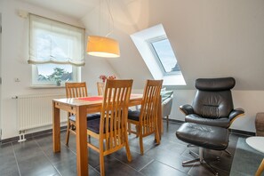 Un comedor con una mesa, sillas, una lámpara colgante y vistas a través de un tragaluz.