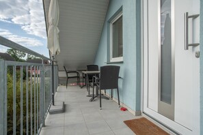 Un espacio exterior techado con una mesa y sillas, una puerta y una ventana.